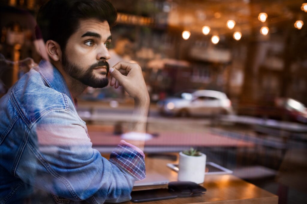 Young man thinking by the bar window