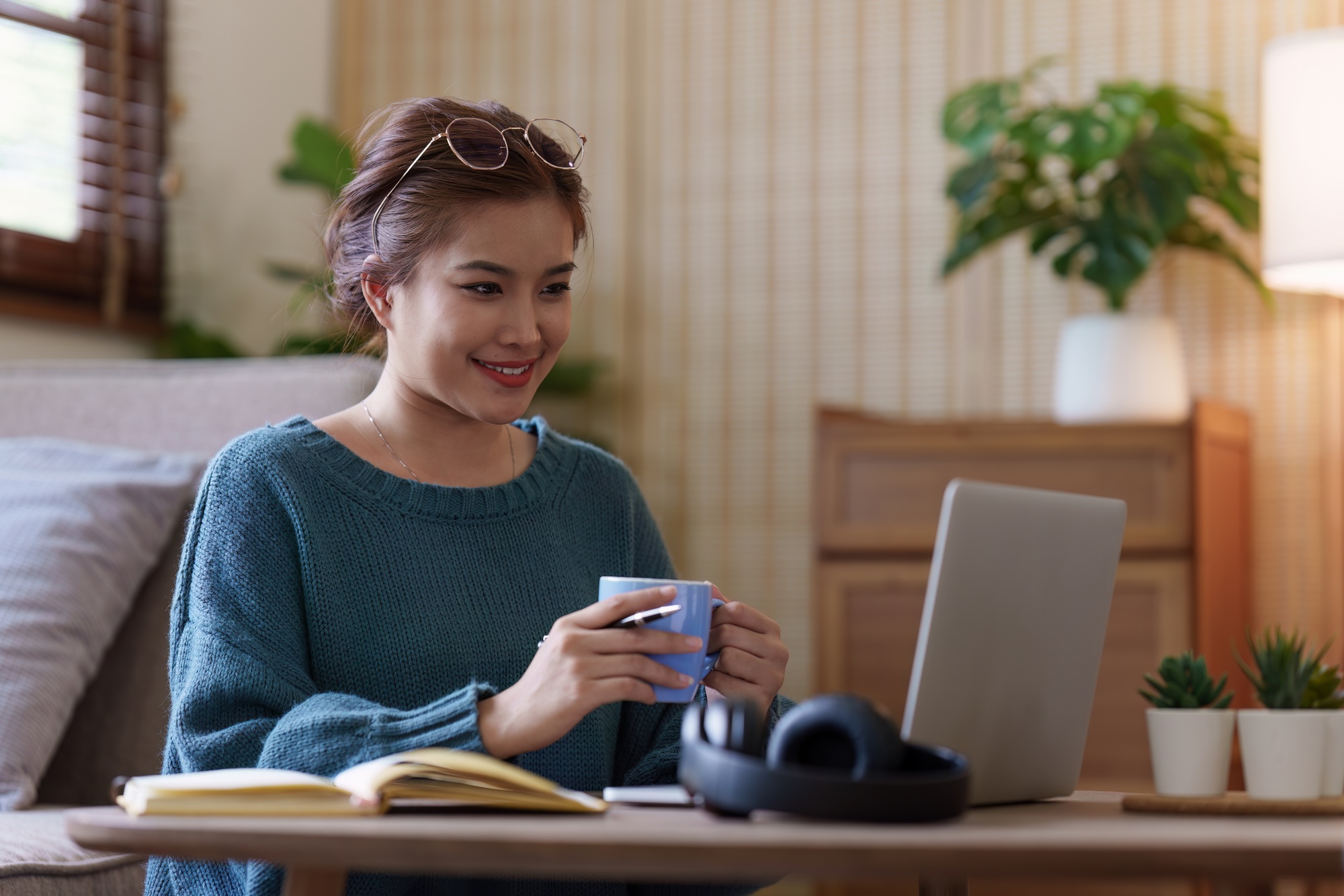 Young asian relaxed smiling pretty woman relaxing with laptop at home. Female feeling joy enjoying