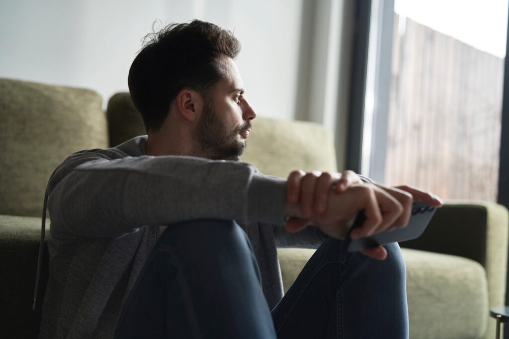 Anxious man at home sitting on floor
